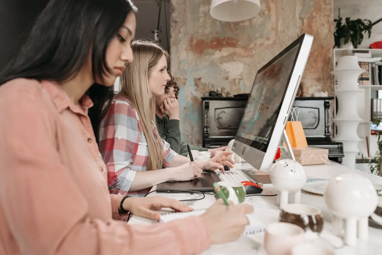 Three young professionals collaborate with technology in a stylish office setting, fostering creativity.
